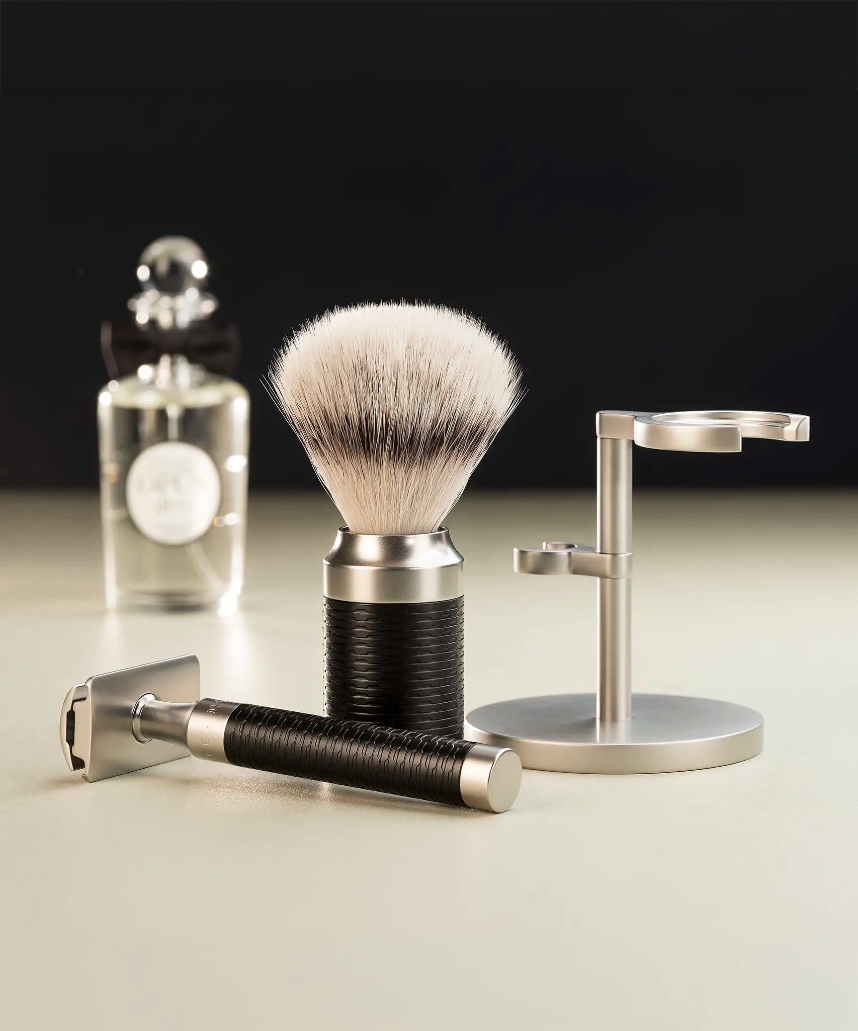 Muhle Rocca black and stainless steel safety razor next to a maching shaving brush with silvertip synthetic fibres and stand