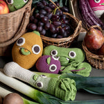 Myum handmade organic cotton soft crochet vegetable toys laid out on a table around real fruit and vegetables