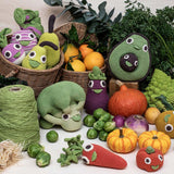 Myum handmade crochet soft vegetable toys laid out on a pile of real vegetables on a white table