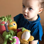 Girl holding a wooden basket full of Myum eco-friendly crochet soft toys on a beige background