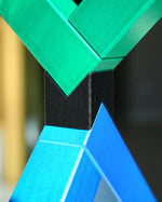 Angular construction toy from Naef arranged in a complex geometric stack in front of a white background.