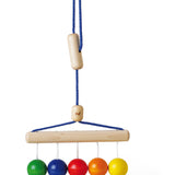 Naef's Colour Balls wooden baby rattle hanging from its string on a white background.