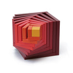 Naef's Cella cube in red twisted to make a swirling pattern from the different cube pieces. Cube is placed on a white background.