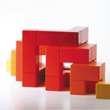 Red Naef Cubicus toy ungrouped and positioned to make a pyramid like shape on a white background.