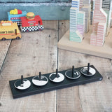 Naef wooden monochrome optical illusion spinning top set sitting on the black holder with vehicles and building blocks in the background