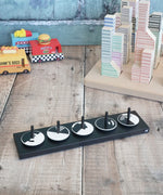 Naef wooden monochrome optical illusion spinning top set sitting on the black holder with vehicles and building blocks in the background