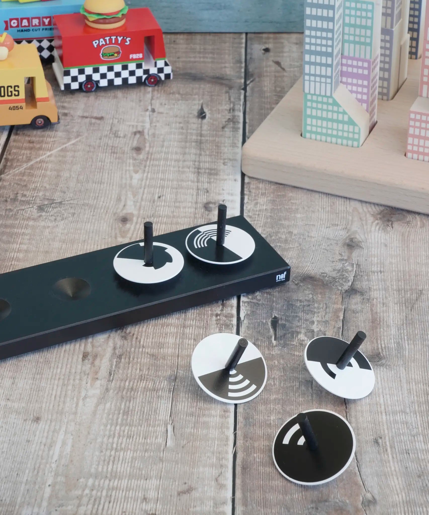 Naef monochrome optical illusion spinning tops loose on a wooden surface 