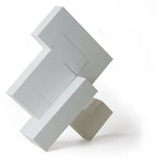 4 pieces of Naef's Quadrigo toy assembled to make a geometric shape titled diagonally.
