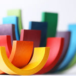 9 piece Naef wooden rainbow stacked on top of each other to form a colourful tower on a white background.