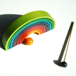 9 pieces of Naef's stacking wooden rainbow upturned on a white background.