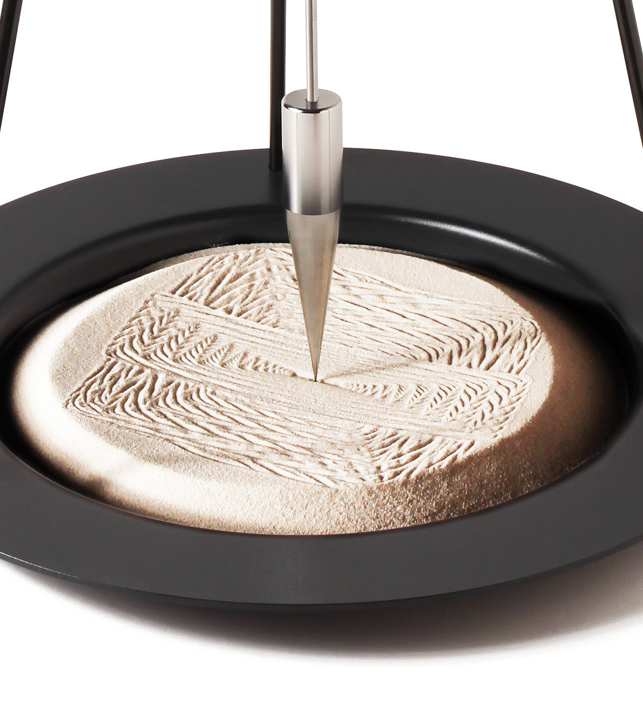 A closeup of the precise and satisfying geometric patterns created in the sand of the Naef Sand Pendulum.