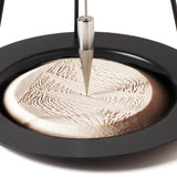 A closeup of the precise and satisfying geometric patterns created in the sand of the Naef Sand Pendulum.
