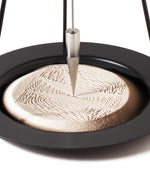 A closeup of the precise and satisfying geometric patterns created in the sand of the Naef Sand Pendulum.