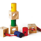 Naef Signa wooden threading toy partially assembled on a white background. Shows 4 wooden cubes and 4 wooden cylinders with thread weaving through holes in the wood.