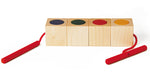 Naef Signa wooden threading toy lined up in a line on a white background. Shows 4 wooden cubes in a line with cylcinders slotted into holes within the cubes. The thread is shown running through all the wooden pieces.
