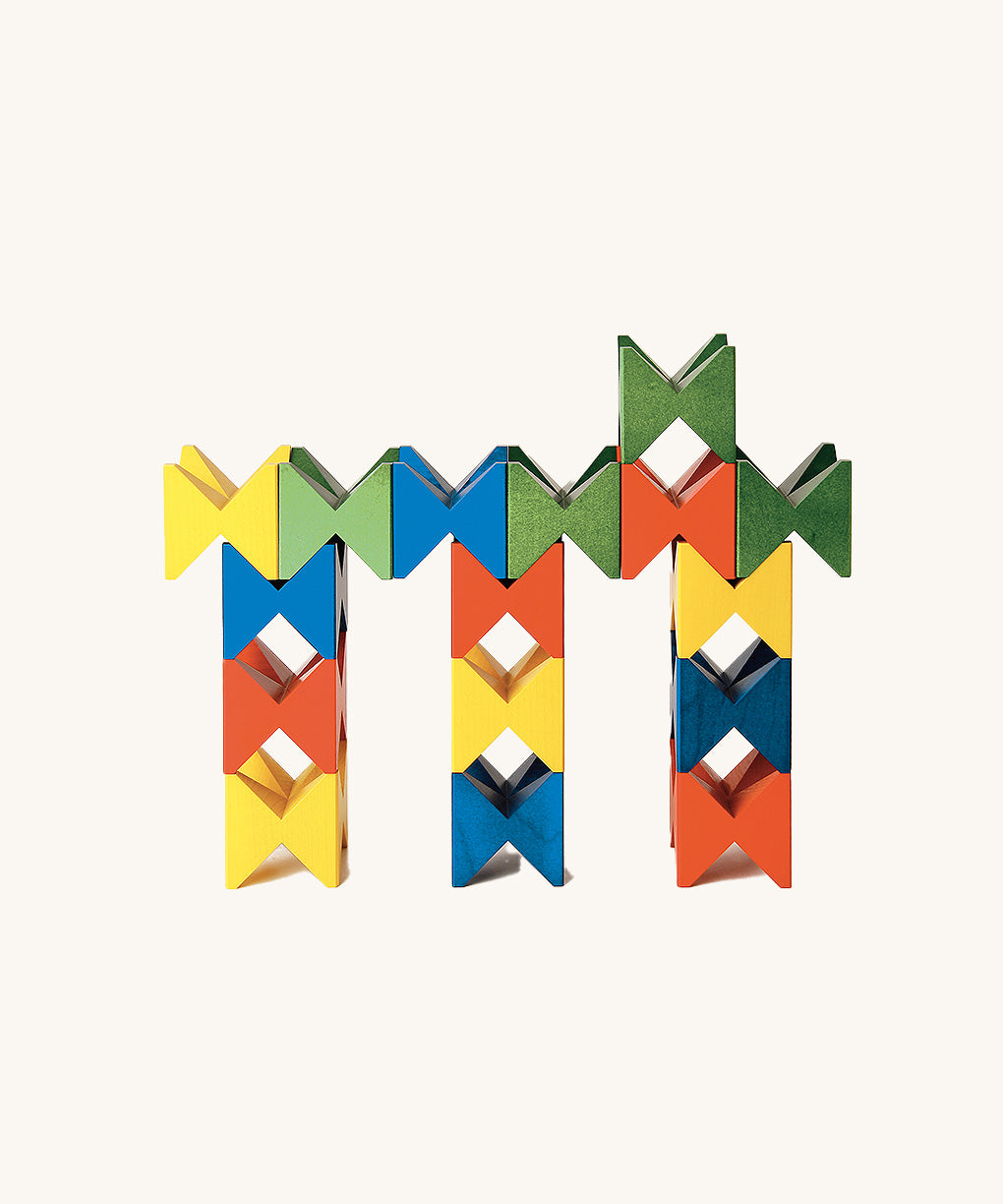 Colourful geometric structure built from Naef Spiel Mini precision wooden blocks in red, blue, yellow, and green. Modern German made wooden puzzle and desk toy.