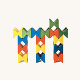 Colourful geometric structure built from Naef Spiel Mini precision wooden blocks in red, blue, yellow, and green. Modern German made wooden puzzle and desk toy.