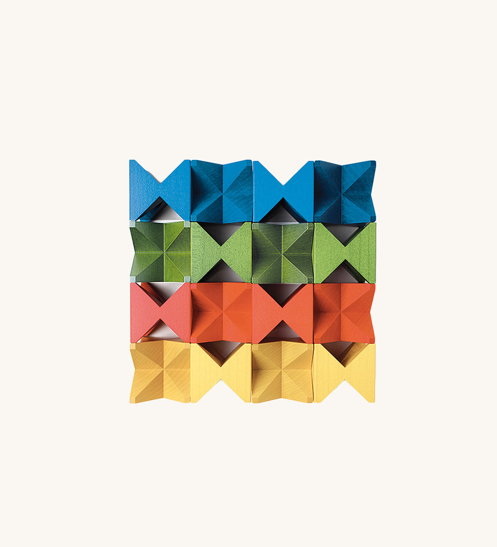 Grid arrangement of Naef Spiel Mini precision wooden cubes in red, blue, yellow, and green. Premium German made desk toy and stacking puzzle.