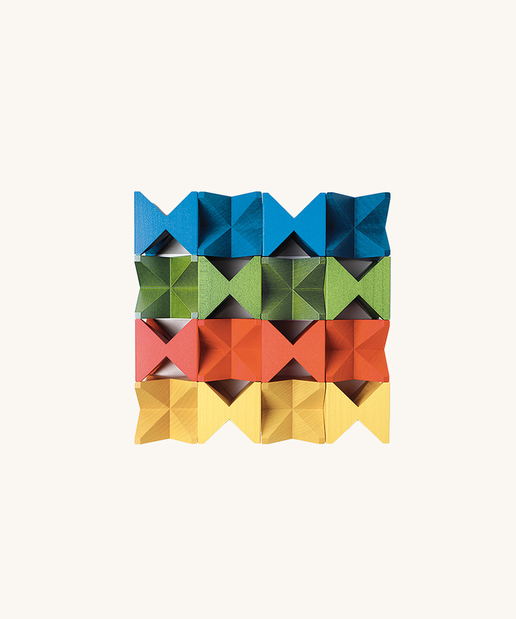 Grid arrangement of Naef Spiel Mini precision wooden cubes in red, blue, yellow, and green. Premium German made desk toy and stacking puzzle.