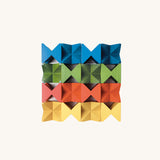 Grid arrangement of Naef Spiel Mini precision wooden cubes in red, blue, yellow, and green. Premium German made desk toy and stacking puzzle.
