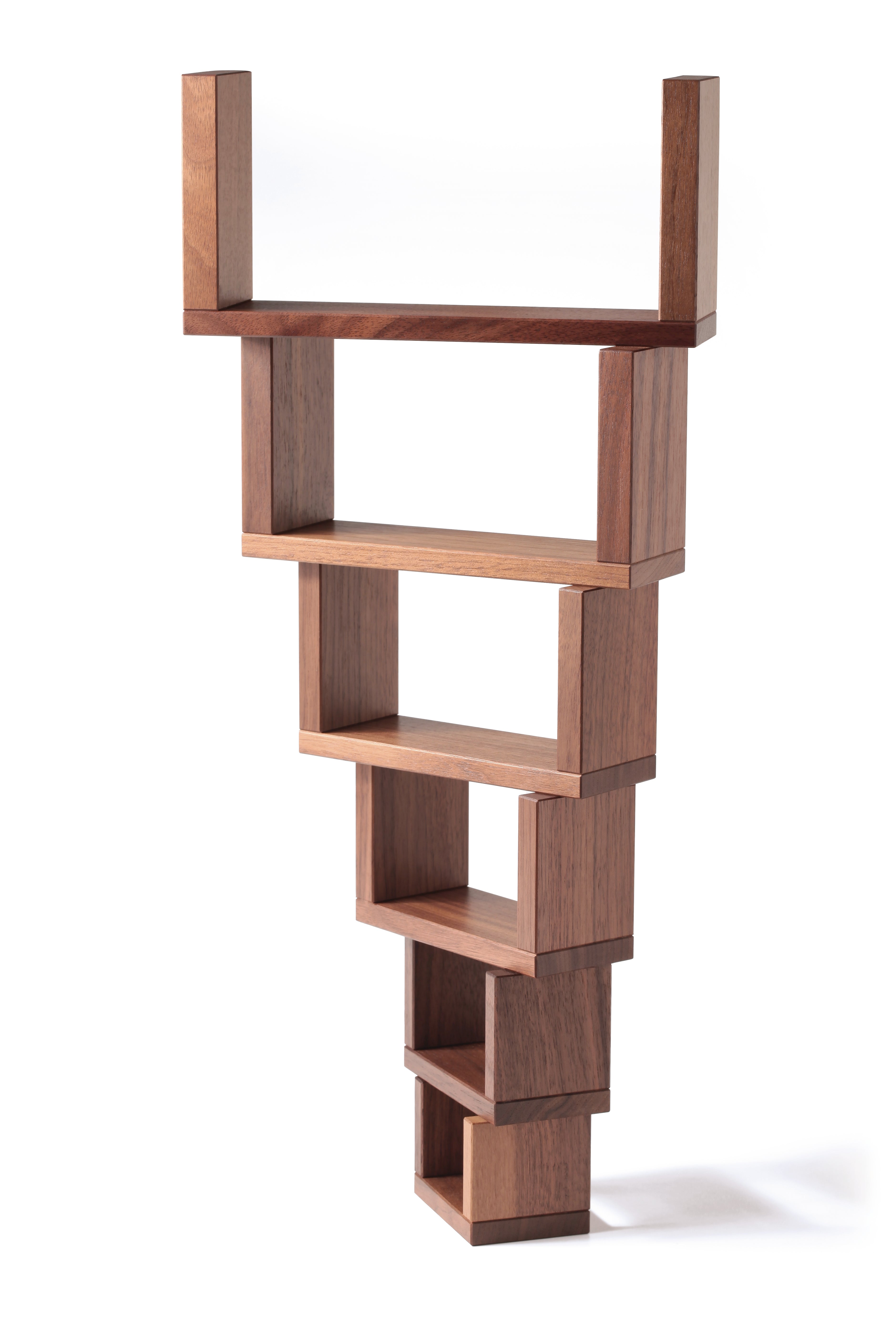 The Naef Corus wooden walnut stacking blocks, stacked high with the smallest piece on the bottom of the stack, and the largest piece balancing on the top. 