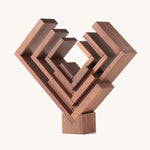 The Naef Corus walnut wood stacking toy, stacked on top of the cubic keystone to create a mesmerising geometric sculpture.