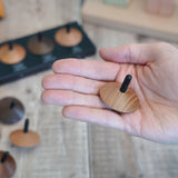 Adult hand holding a loose Naef wooden spinning top 