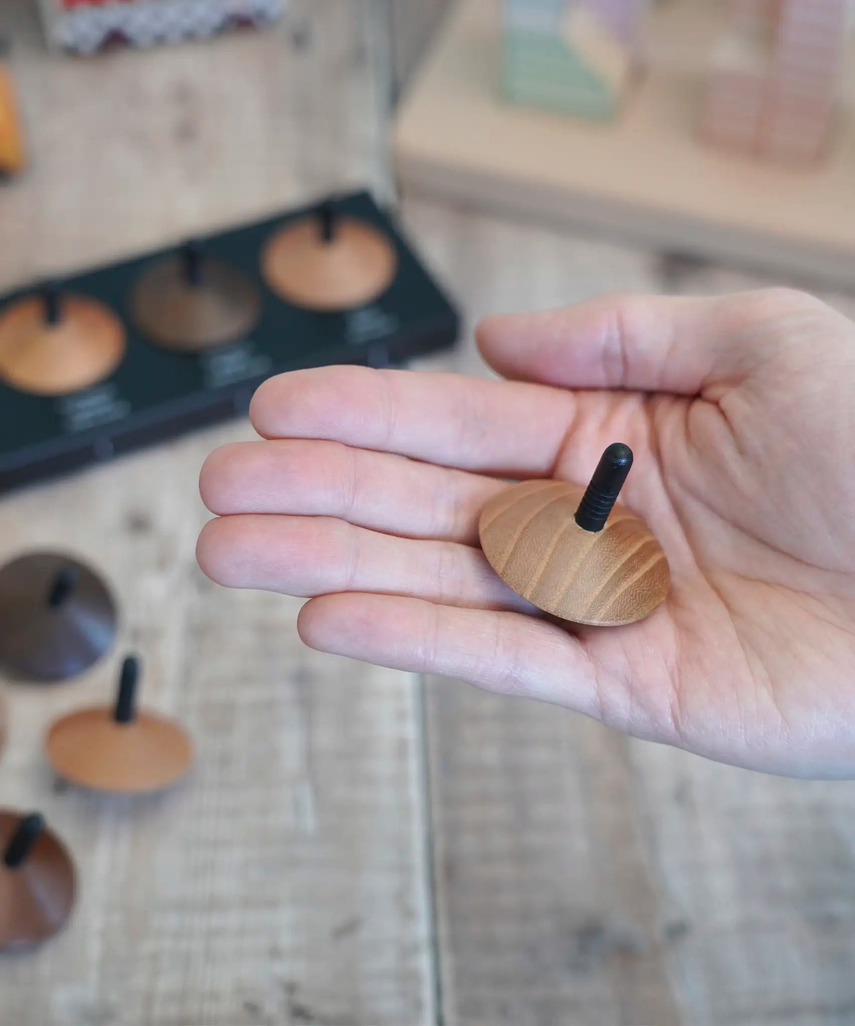Adult hand holding a loose Naef wooden spinning top 