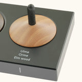 Corner detail of the Naef wooden spinning top holder showing a elm wood spinning top and description