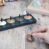 Adult hand holding a loose handcrafted wooden Naef spinning top next to other wooden spinning tops