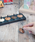 Adult hand holding a loose handcrafted wooden Naef spinning top next to other wooden spinning tops