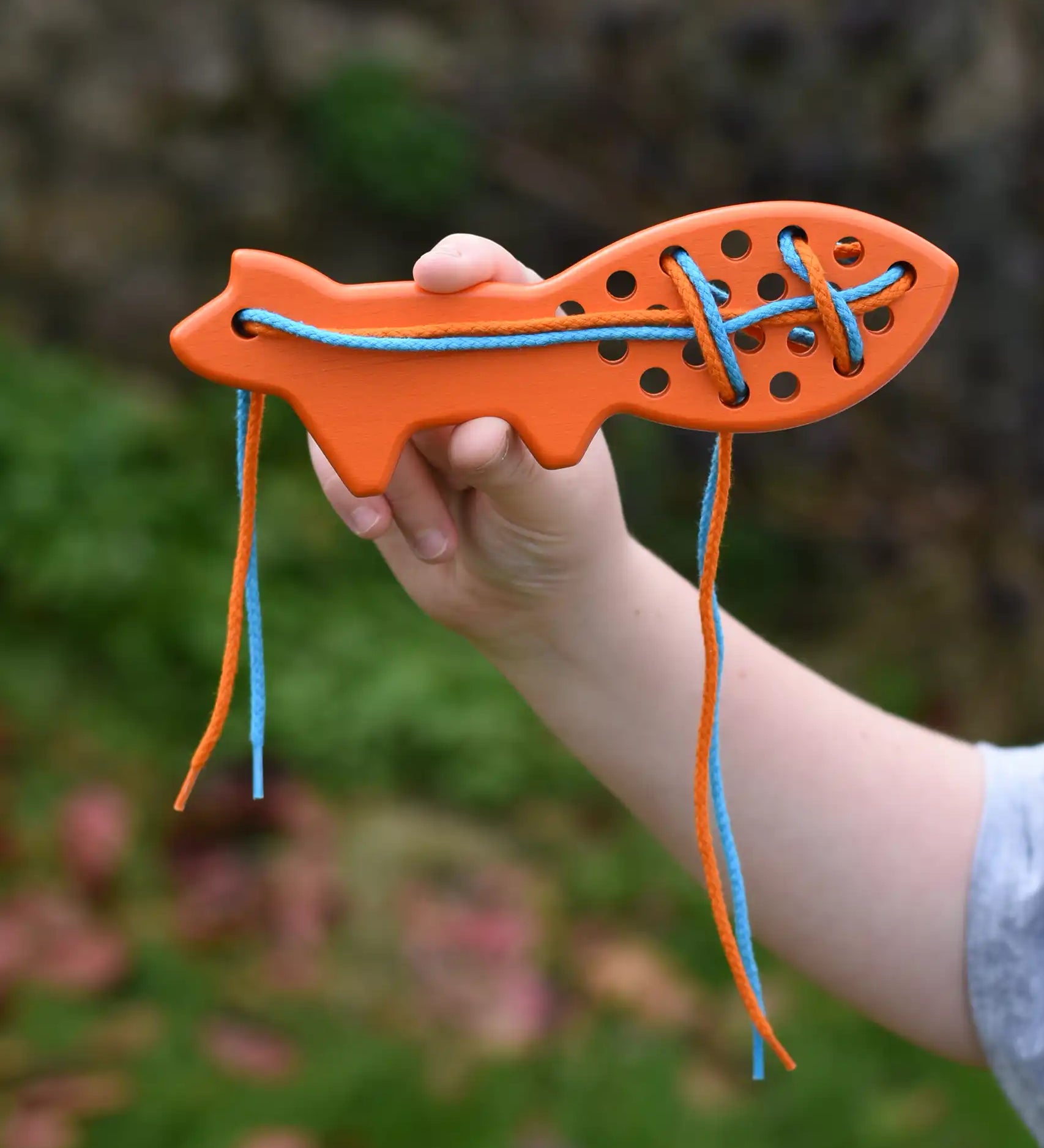Bajo orange lacing fox wooden toy in a child's hands.