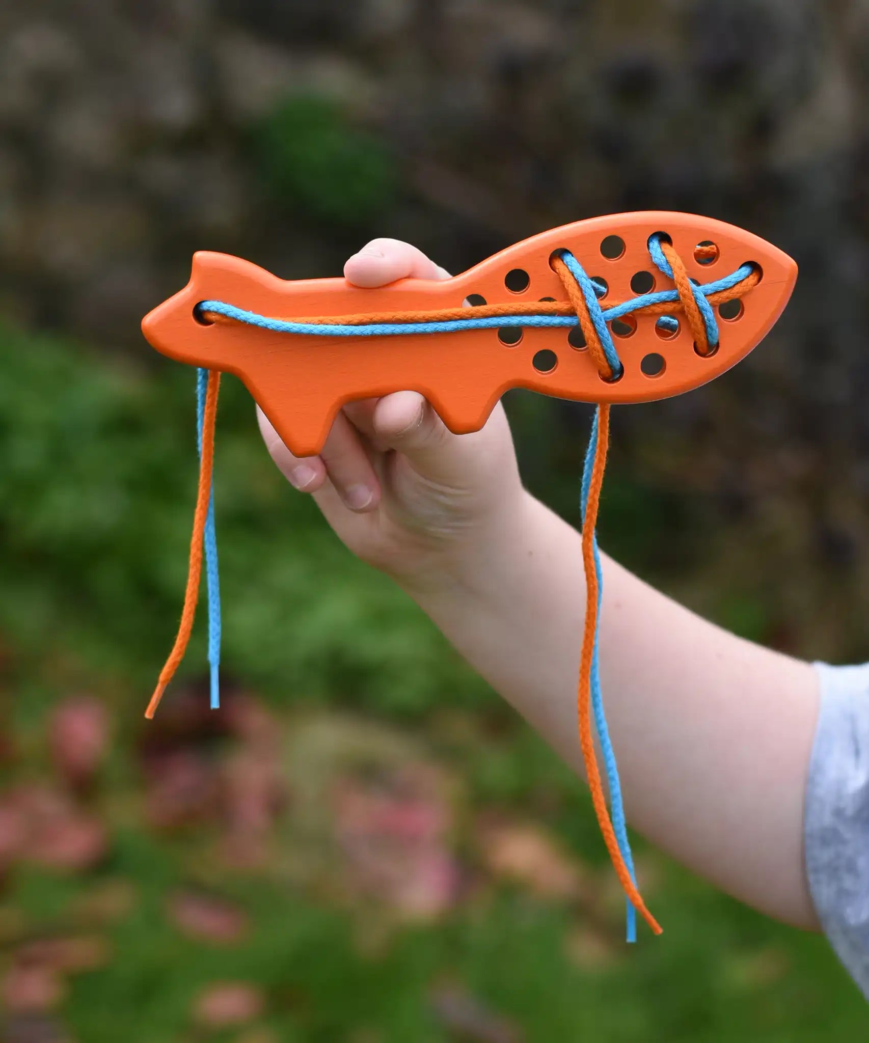Bajo orange lacing fox wooden toy in a child's hands.