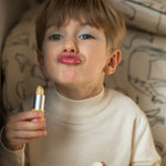 A child's wearing the Namaki child friendly lip balm on their lips holding the balm packaging in their hand 
