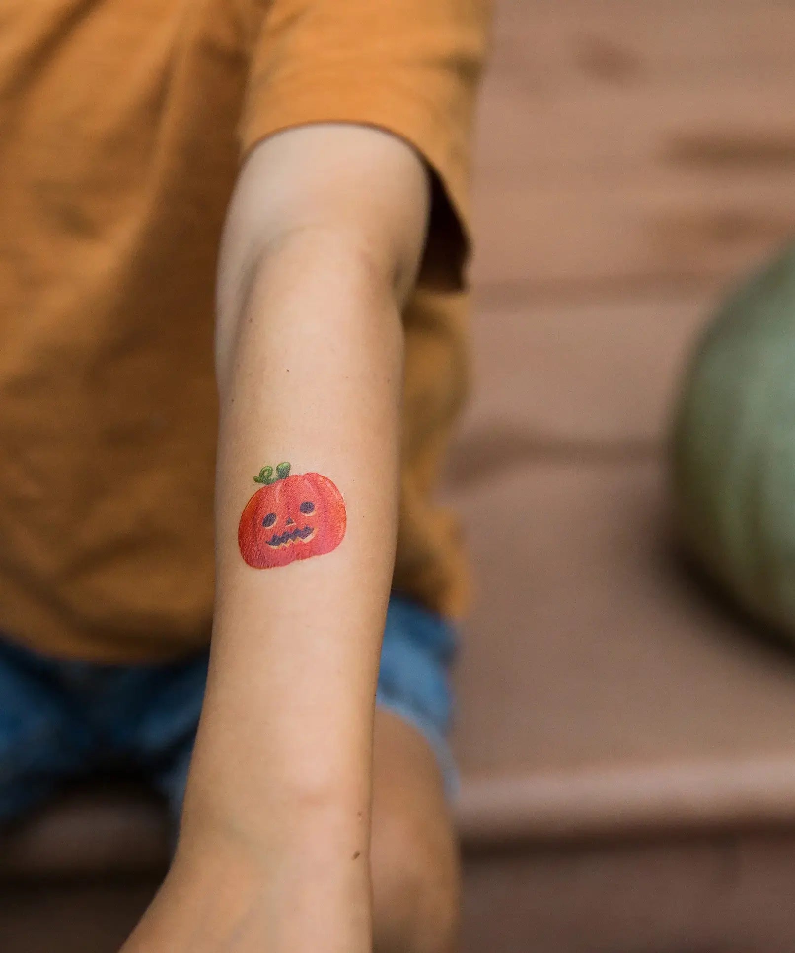 Pumpkin tattoo from the Namaki Halloween face painting kit applied to a child's arm.
