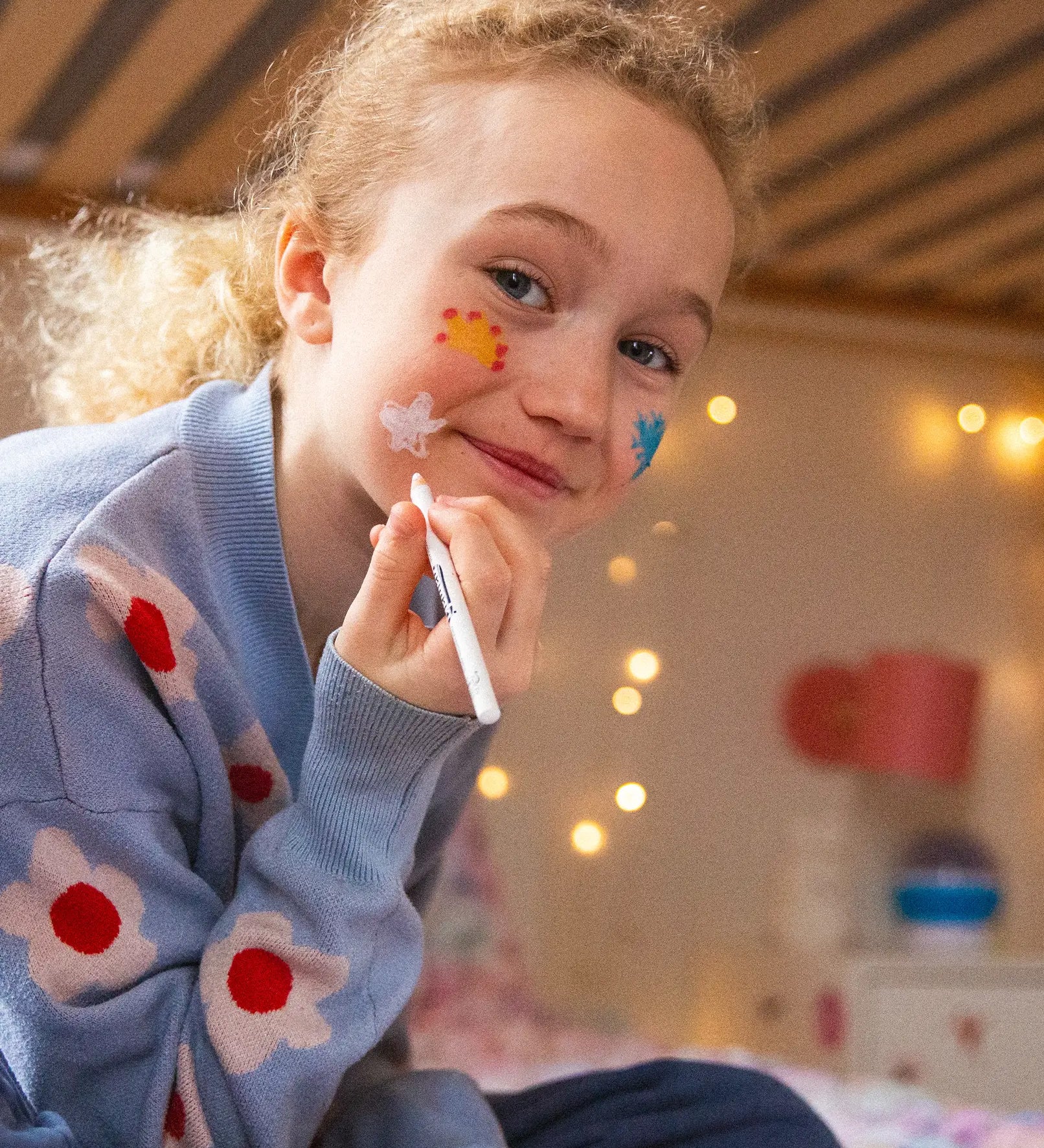 A girl drawing on her face with the Namaki natural and organic face painting pencils