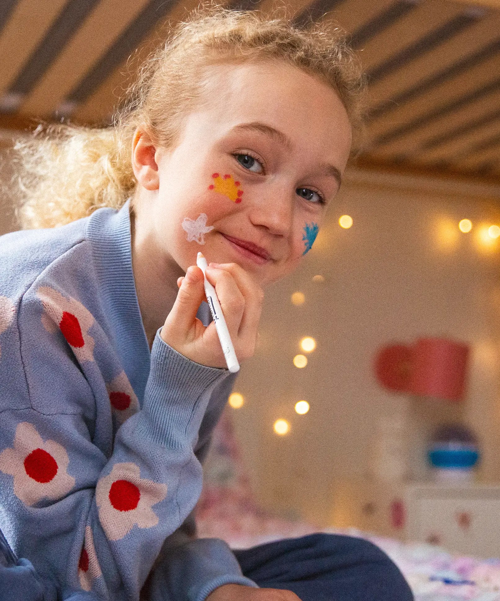 A girl drawing on her face with the Namaki natural and organic face painting pencils