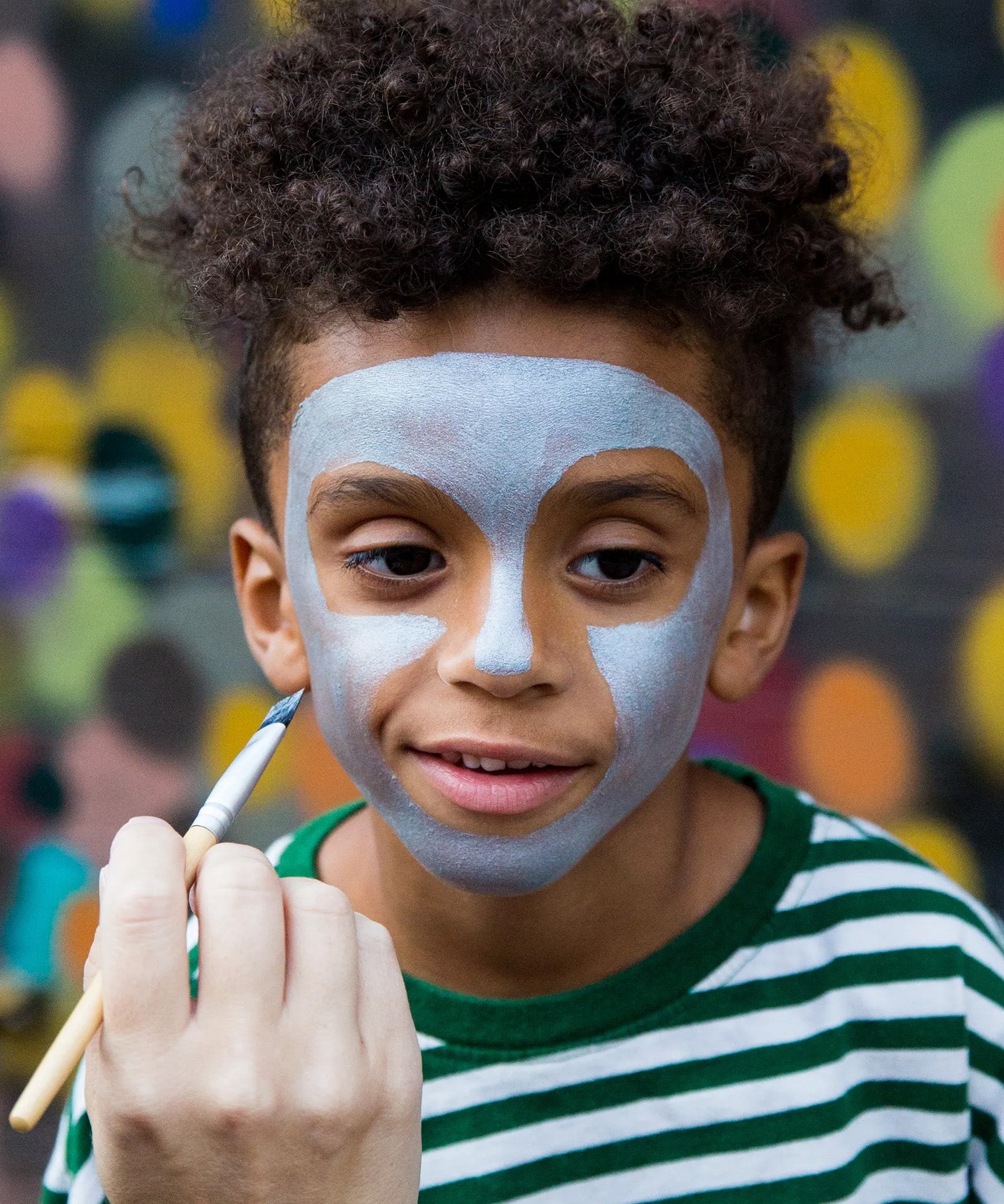 Child having face painted with Namaki natural water-based kids' blue face paint .