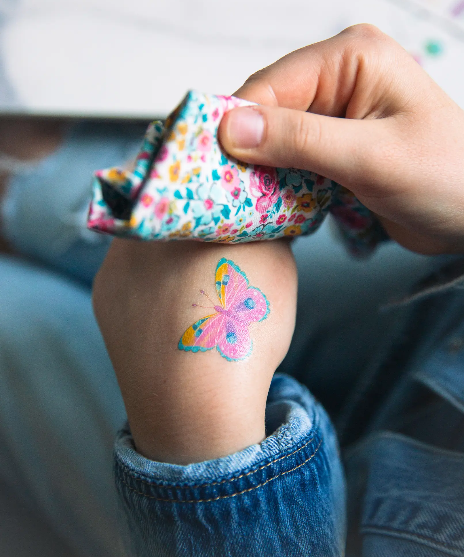 A closeup of a child's hand, applying a Namaki non-toxic temporary butterfly tattoo. 