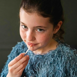 A girl applying the Namaki natural and organic kids' lip gloss in a sparkly peach colour. 