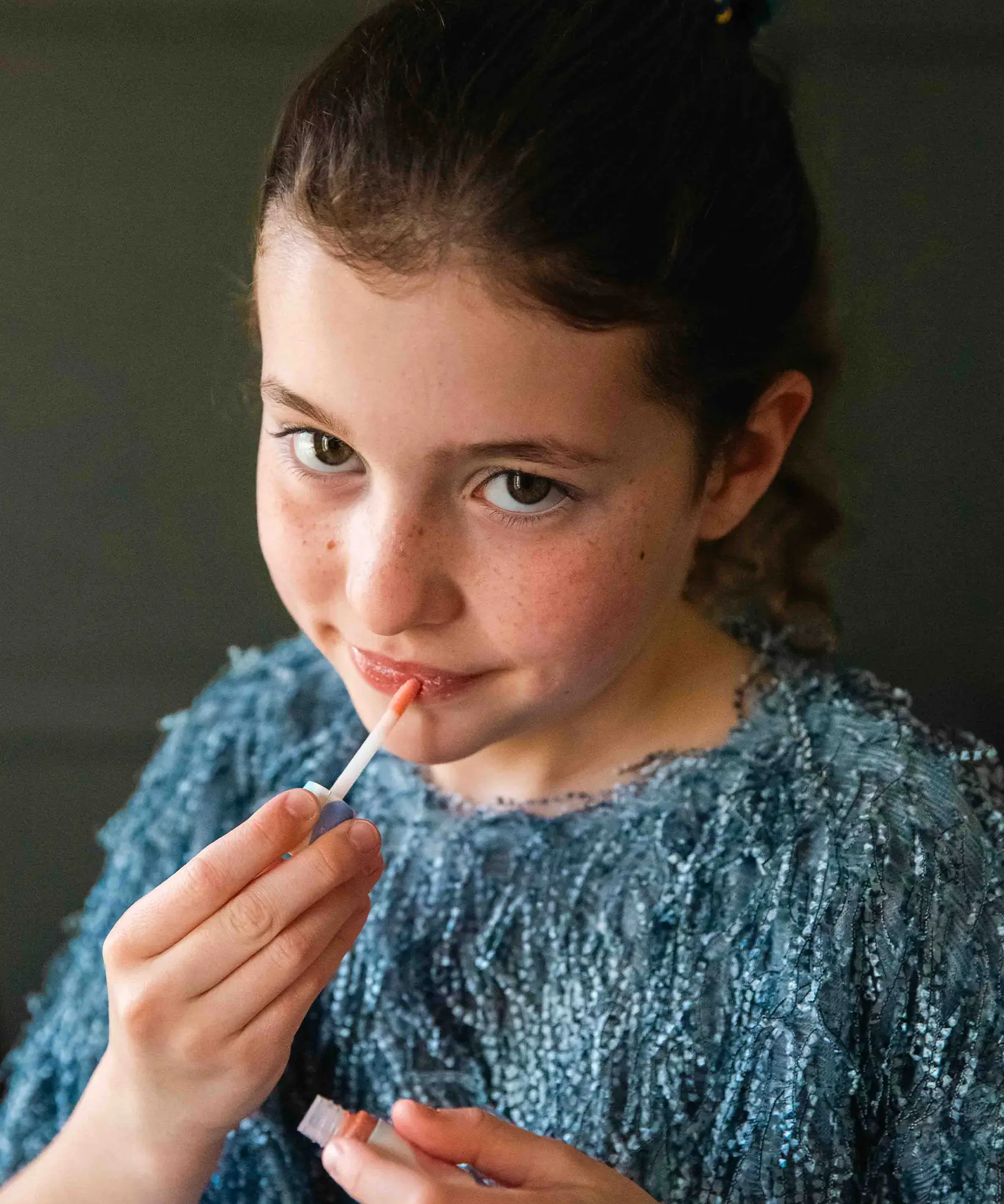A girl applying the Namaki natural and organic kids' lip gloss in a sparkly peach colour. 
