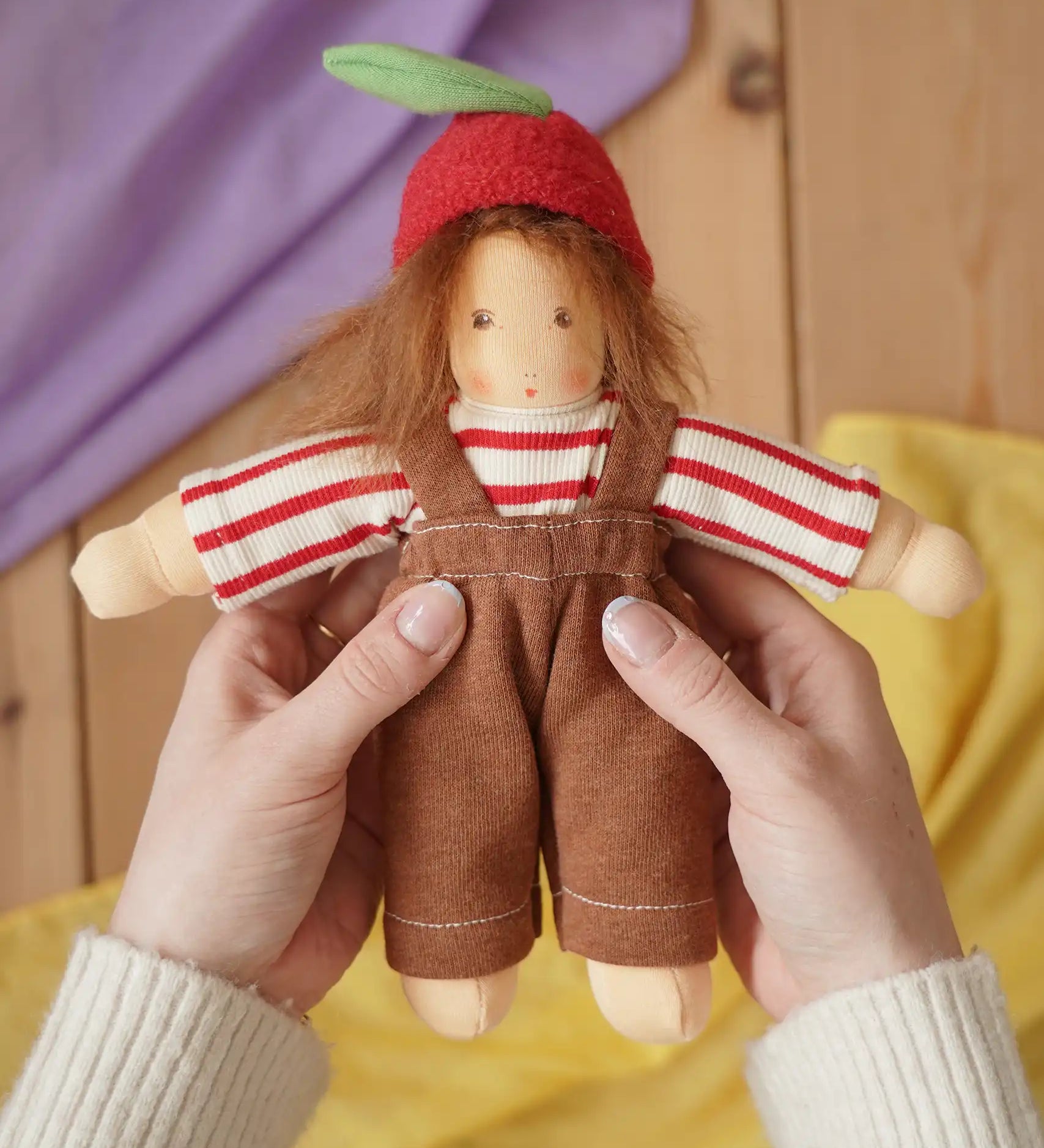 Nanchen apple child Waldorf doll  Anna in an adults's hand in the Babipur playroom.
