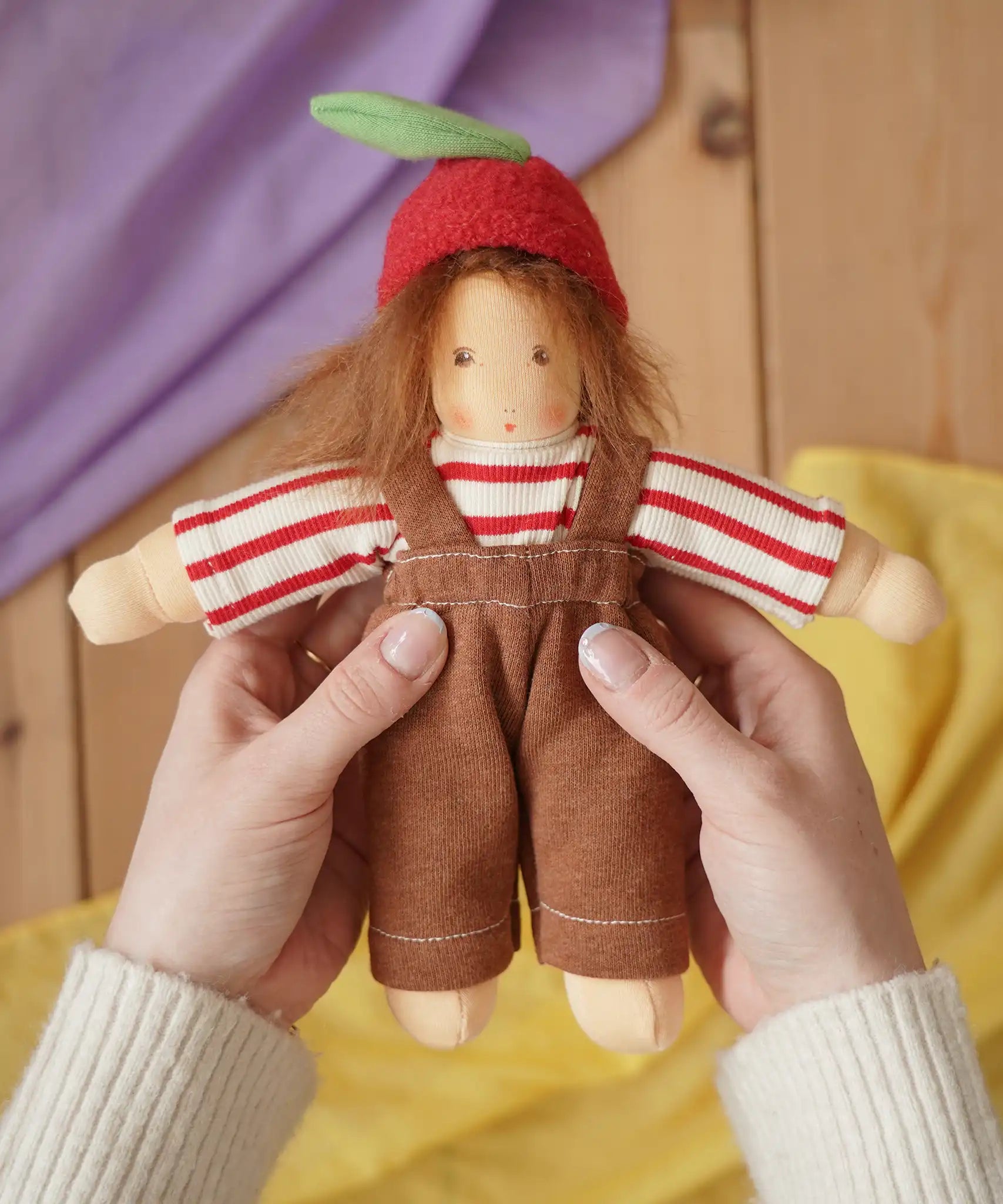 Nanchen apple child Waldorf doll  Anna in an adults's hand in the Babipur playroom.