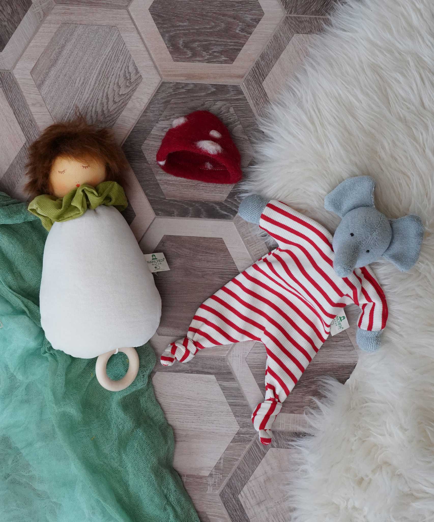 A Nanchen toadstool lullaby music toy next to a Nanchen elephant baby comforter soft toy.