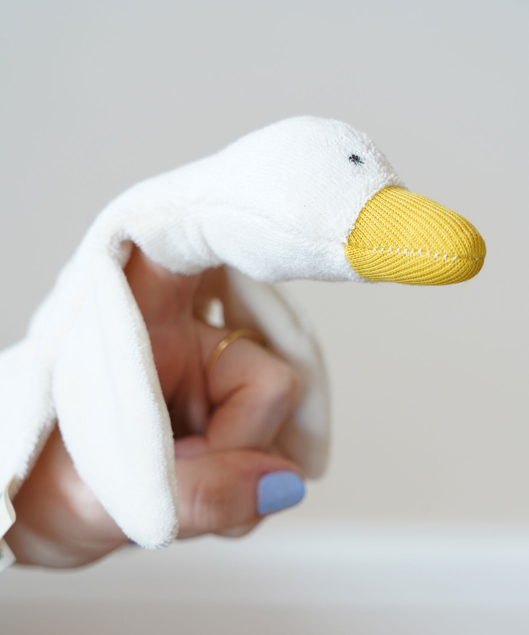 A close up of the goose's head on the Nanchen white goose baby comforter. There is a small pocket in the material allowing the goose to be used as a puppet.