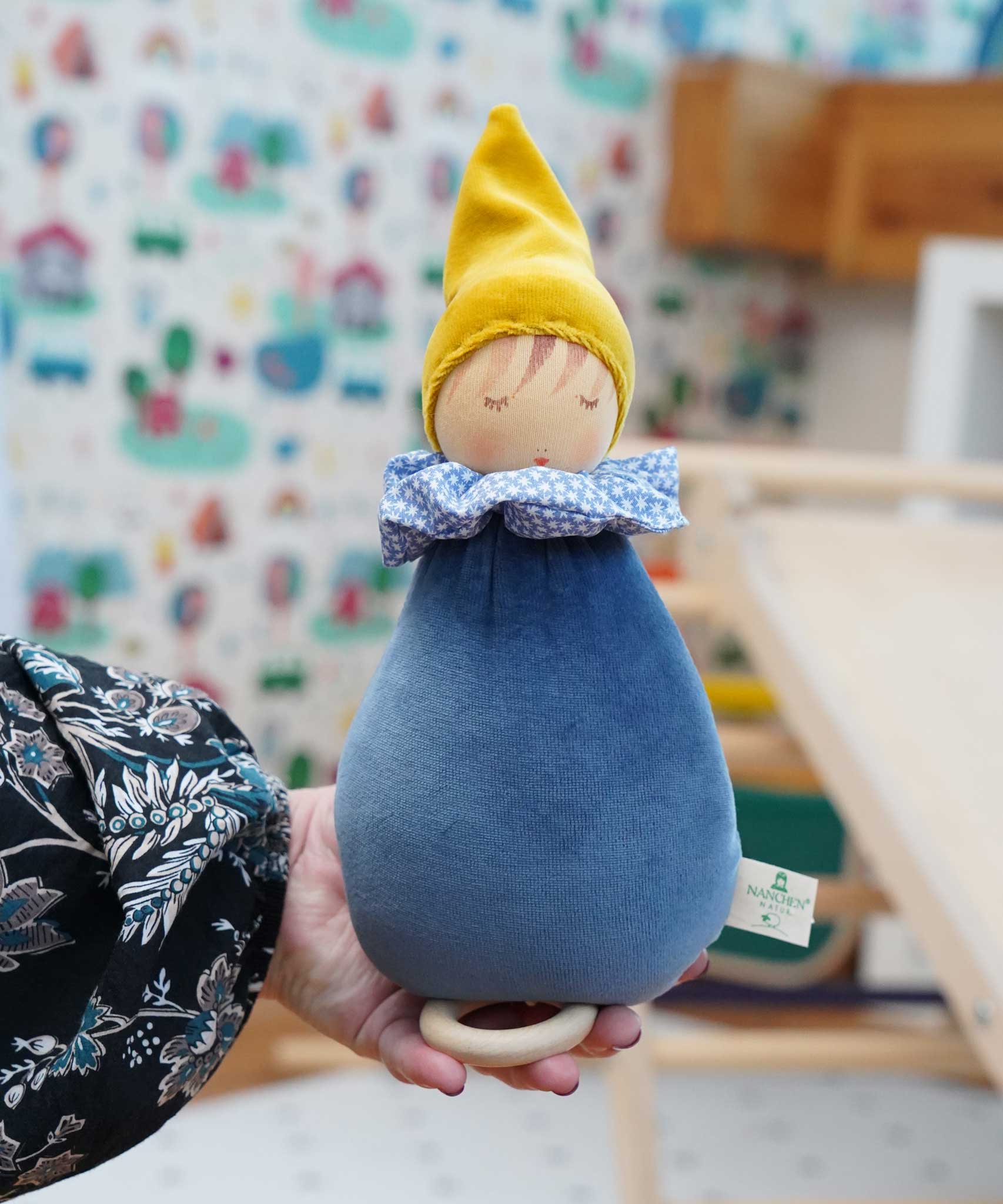 A close up of a Nanchen Dream King Frog Lullaby Music Doll in a child's hand. A musical Waldorf doll, made from organic cotton and sheep's wool. 