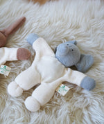 A Nanchen Elephant Teddy Rattle placed on a sheepskin rug.