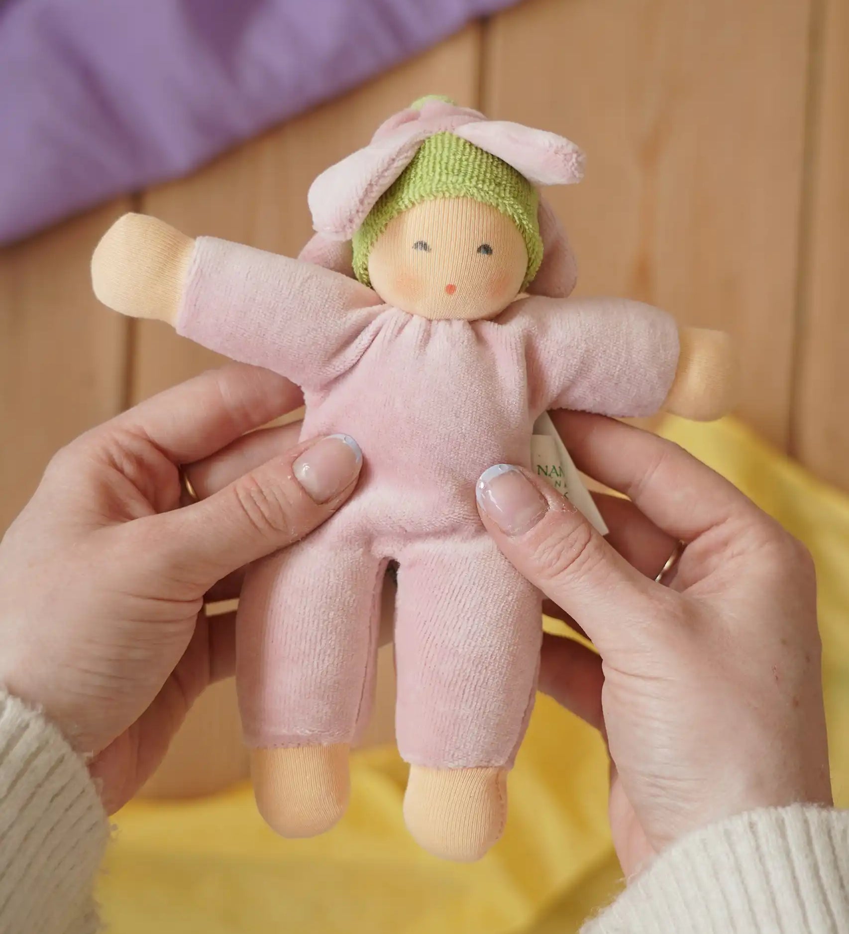 Nanchen flower fairy Waldorf rattle doll in an adult's hands in the Babipur playroom.