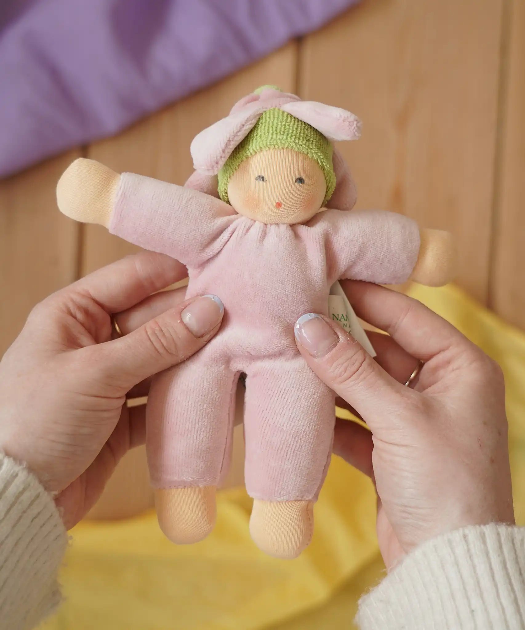Nanchen flower fairy Waldorf rattle doll in an adult's hands in the Babipur playroom.