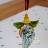 The Nanchen green Flower Fairy Ring Grasper shown suspended from a piece of red velvet ribbon. 